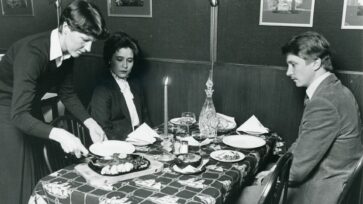 Mustavalkoinen kuva pariskunnasta aterioimassa ravintolassa.