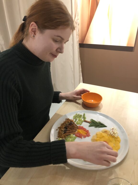 Ruokataidepajan osallistuja asettelee lautaselle syötäviä raaka-aineita, jotka muodostavat taideteoksen.